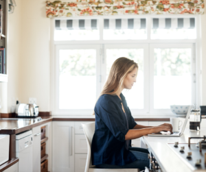 A woman sitting at her kitchen counter working on her laptop