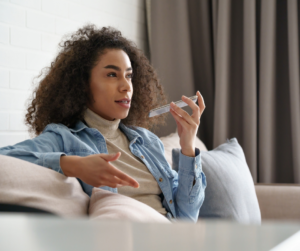 A female virtual assistant sitting on a couch talking into her phone