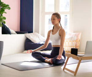 A woman sitting in a seated position taking a break on her yoga mat 