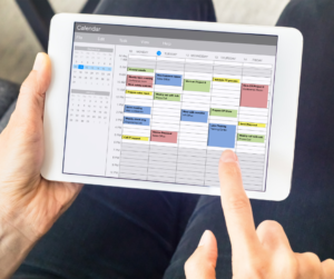 A person on their tablet organising their monthly calendar