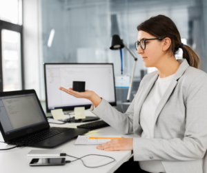 A female virtual assistant in a grey jacket sitting at her desk