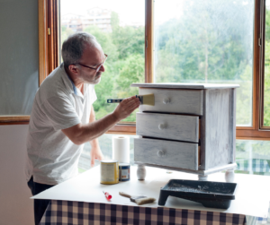 A man painting a chest of drawers