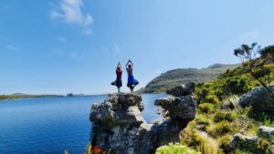 Two women standing on a rock doing a yoga pose