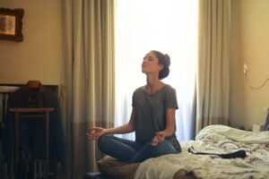 Woman meditating on her bed managing work-life balance