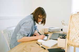 Female virtual assistant writing on paper to help manage work-life balance