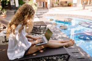 self-employed woman sitting on her laptop at a pool taking a sabbatical
