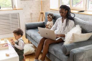 Woman with her two kids sitting on a couch on her laptop