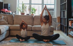 A mom and daughter sitting on the floor doing yoga