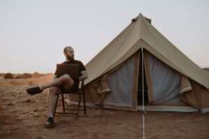 Man on his laptop taking a sabbatical sitting outside his tent in the desert