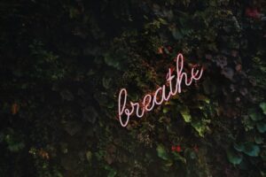 Neon sign on a wall reading "breathe"