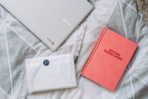 A diary and laptop on a bed showing how to be less busy